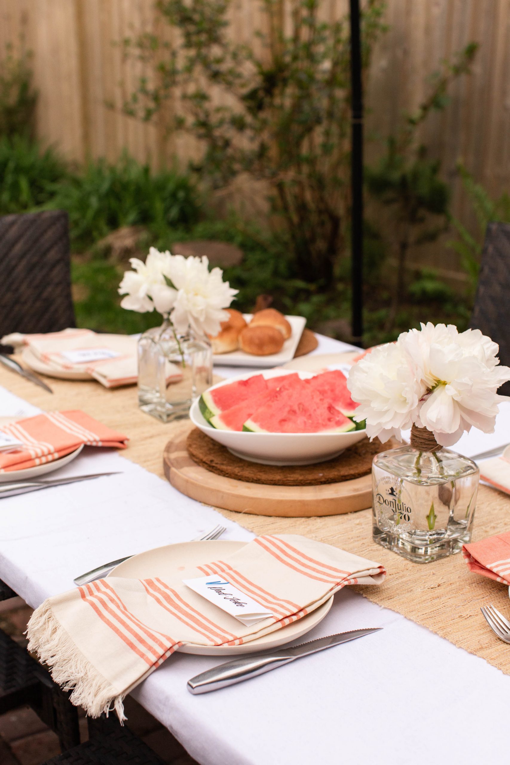 coral and cream tablescape with buns and watermelon. Peonies in old tequila and scotch bottles-3