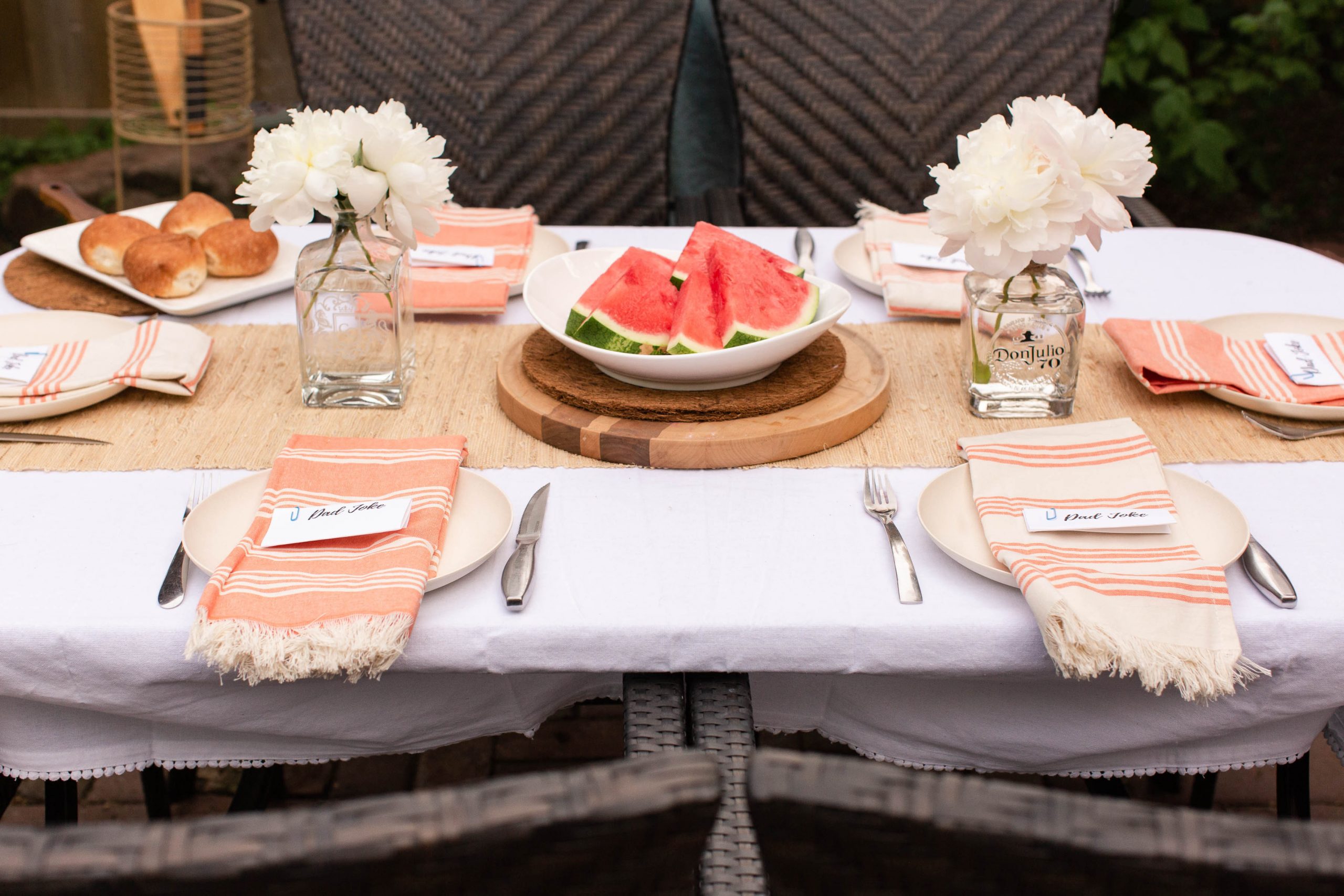 coral and cream tablescape with buns and watermelon. Peonies in old tequila and scotch bottles-2